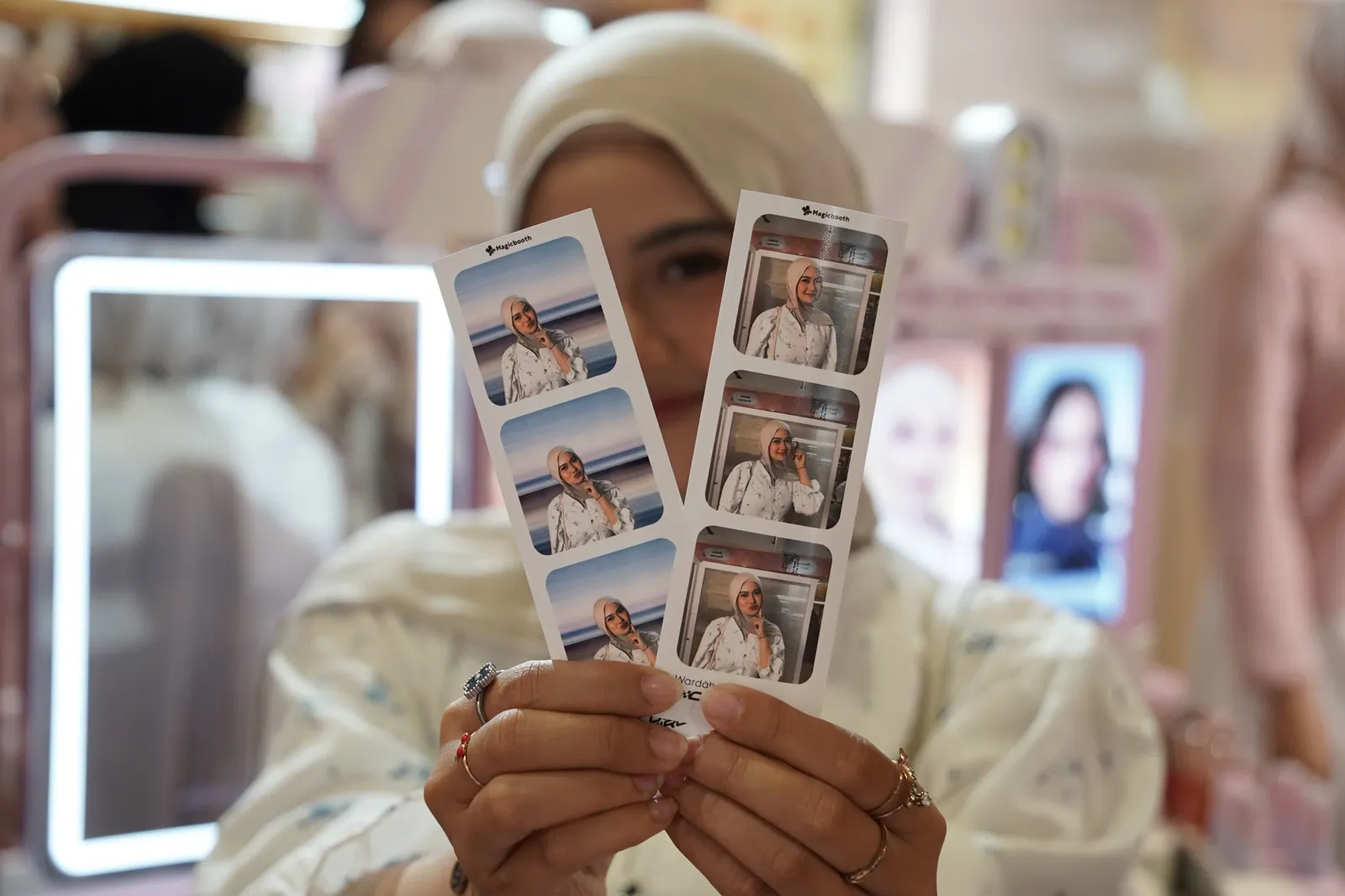 A visitor holding two branded photostrips from Magicbooth